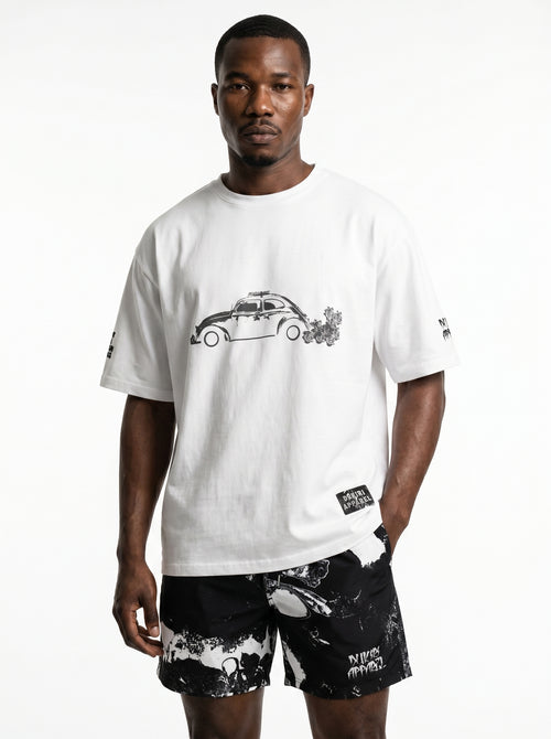 Man wearing a white t-shirt with a graphic design and black shorts on a white background