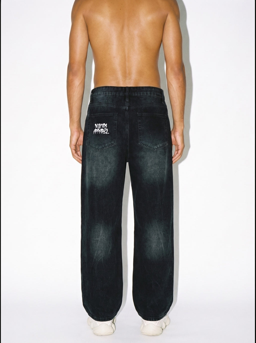 Man wearing White Lotus vintage washed wide leg denim jeans with his back turned revealing a Dukiri Apparel logo on the pockets