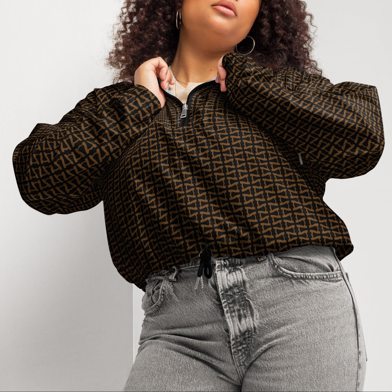 Woman wearing a patterned brown jacket and gray jeans against a plain background