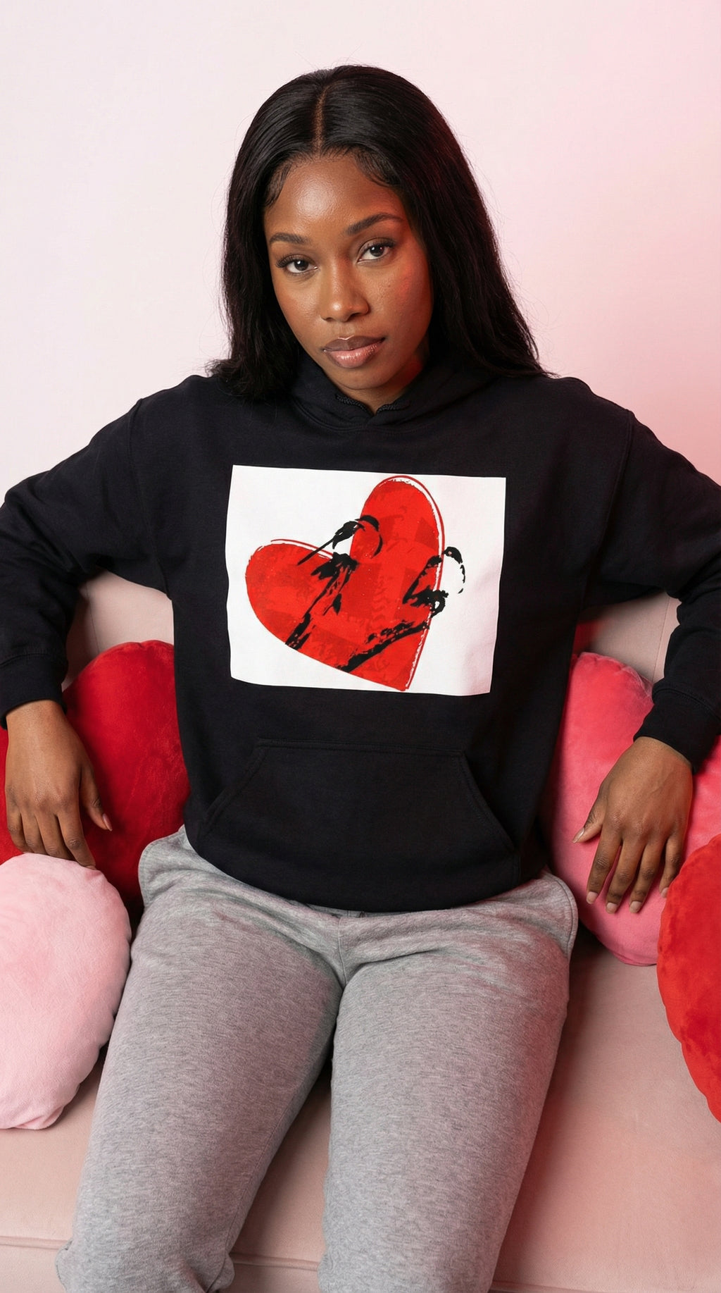 Person wearing a black hoodie with a graphic design on a pink couch
