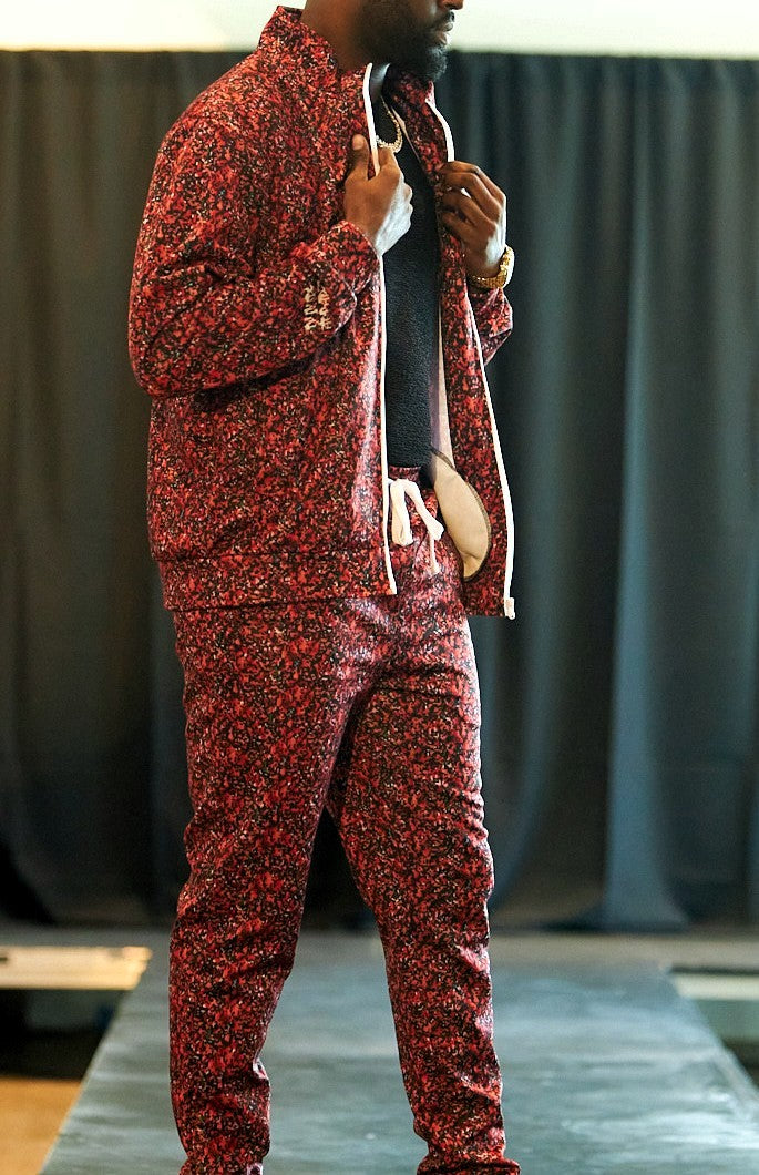 Person wearing a red patterned tracksuit standing against a plain background