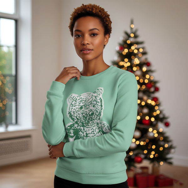 Woman wearing a light blue sweater with a white design in front of a decorated Christmas tree.