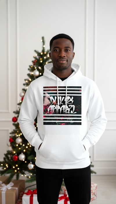 Person wearing a white hoodie with graphic design in front of a decorated Christmas tree.