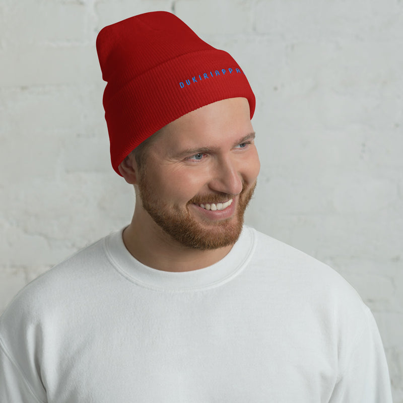 a man wearing a red beanie smiles at the camera